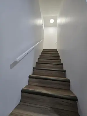 a staircase with wooden floors and a white wall at Clearwater Chestermere in Chestermere