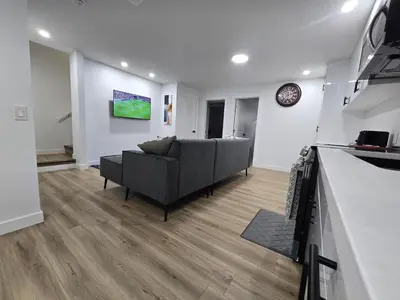 a living room with a couch and a clock on a wall at Clearwater Chestermere in Chestermere