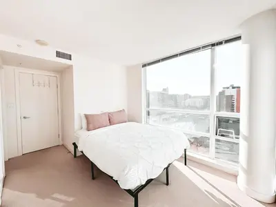 a white bedroom with a bed and a large window at Riverside Mint 2bd den 2 ba in Calgary
