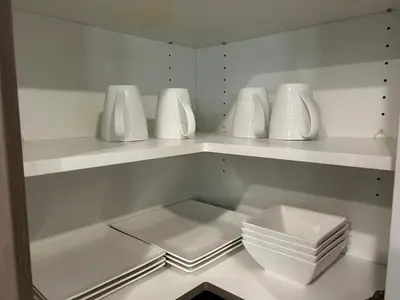 a white kitchen with white bowls and plates on shelves at Family friendly home at Chappelle garden in Edmonton