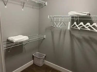 a walk in closet with white towels and a basket at Family friendly home at Chappelle garden in Edmonton