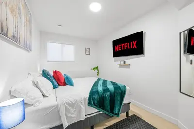 a bedroom with a bed with a television on the wall at Laurel 27BnB in Edmonton