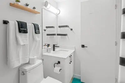 a white bathroom with a sink and a mirror at Laurel 27BnB in Edmonton
