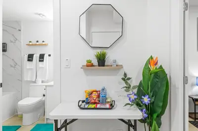 a white bathroom with a table and a mirror at Laurel 27BnB in Edmonton