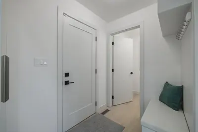 a white hallway with a door and a mirror at Board Games, King Bed, Cocoa Bar, & Firewood! in Calgary