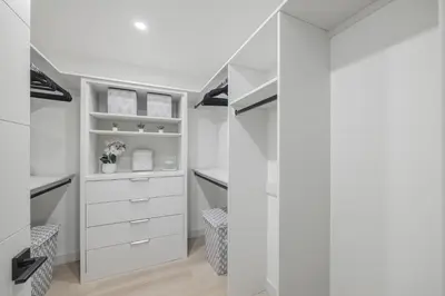 a walk in closet with white cabinets and shelves at Board Games, King Bed, Cocoa Bar, & Firewood! in Calgary
