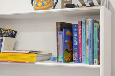 a row of books on a book shelf at 2 bed Suburban Oasis in Surrey in Surrey