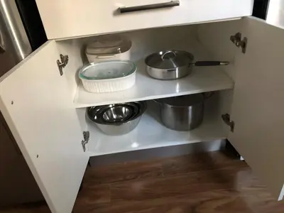 a white kitchen with pots and pans on a shelf at 2 bed Suburban Oasis in Surrey in Surrey