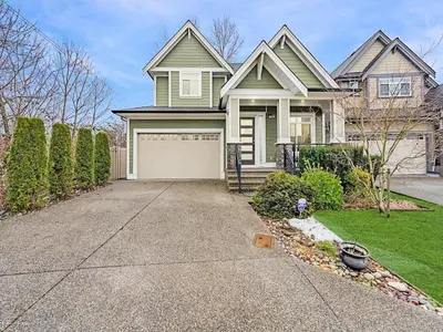 a green house with a garage in the driveway at 2 bed Suburban Oasis in Surrey in Surrey