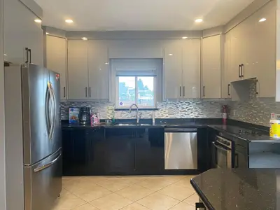a kitchen with black cabinets and a stainless steel refrigerator at 5 Minutes away from Edmonds Station! Ideal location for all events & attractions in New Westminster