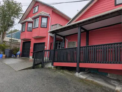 a red house with a black fence in front of it at Executive Suite 2 Bedroom Serviced Apartment in Alert Bay