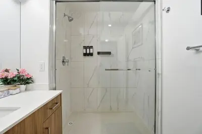 a white bathroom with a shower with a glass door at Luxury 1Beds and 2Beds in Downtown Edmonton close to Rogers in Edmonton