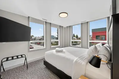 a bedroom with a large bed and windows at Downtown Revelstoke Retreat by Canadian Rockies Vacation Rentals in Revelstoke