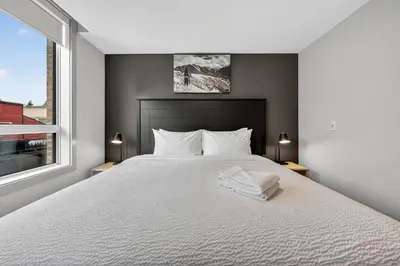a bedroom with a bed with white sheets and a window at Downtown Revelstoke Retreat by Canadian Rockies Vacation Rentals in Revelstoke