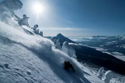 a group of people skiing down a snow covered mountain at Downtown Revelstoke Retreat by Canadian Rockies Vacation Rentals in Revelstoke