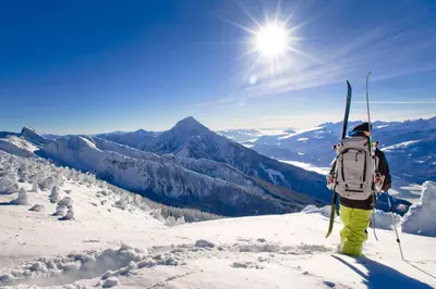 a man with a backpack and skis on a mountain at Downtown Revelstoke Retreat by Canadian Rockies Vacation Rentals in Revelstoke