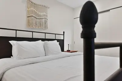 a bed with white sheets and a black head board at The Landing- Your Downtown Waterfront Oasis in Tofino