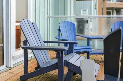 two blue chairs and a table on a balcony at The Landing- Your Downtown Waterfront Oasis in Tofino