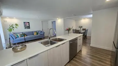 a kitchen with a sink and a living room with a couch at Family Home in North Vancouver