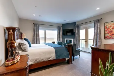a bedroom with a bed and a chair and windows at Blue Horizon Mountain Retreat B&B in Shawnigan Lake