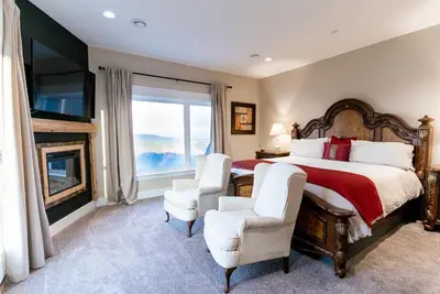 a bedroom with a bed and two chairs and a fireplace at Blue Horizon Mountain Retreat B&B in Shawnigan Lake