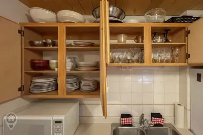 a kitchen with wooden cabinets and plates and a microwave at Pet-Friendly Original Ski Cabin by StayIn in Panorama