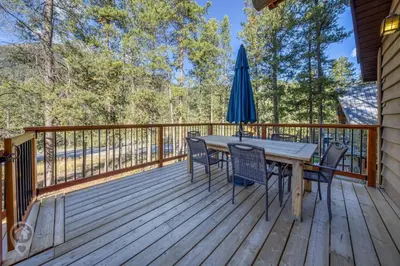 a wooden deck with a table and chairs and an umbrella at Pet-Friendly Original Ski Cabin by StayIn in Panorama