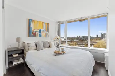 a white bedroom with a bed and a large window at Sunny Corner 1-Bedroom Chinatown and Gastown at Your Doorstep in Vancouver
