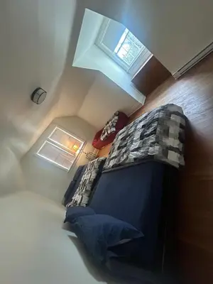 a small attic bedroom with a bed and windows at Vancouver Home - Airport 10 Min, Downtown 15 Min - Free Parking & Fast Wi-Fi in Vancouver