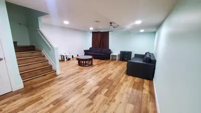 a living room with two chairs and a table and stairs at Entertainment house with 2 king 1 queen 1 sofa bed In-house Theater Attach Garage Near YEG Loved by Guests on Other Plateform in Edmonton