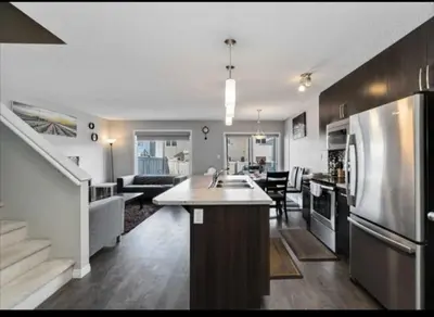 a kitchen and living room with a sink and a stove at Entertainment house with 2 king 1 queen 1 sofa bed In-house Theater Attach Garage Near YEG Loved by Guests on Other Plateform in Edmonton