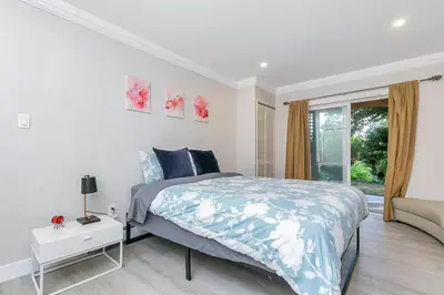 a white bedroom with a bed and a window at Spacious Oceanview Suite with Private Entrance in West Vancouver