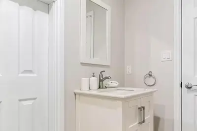a white bathroom with a sink and a mirror at Spacious Oceanview Suite with Private Entrance in West Vancouver