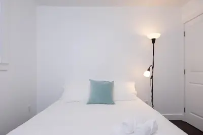 a bedroom with a white bed with a blue pillow at Cozy 2B Suite in Great Location Near Trails & Shop in North Vancouver