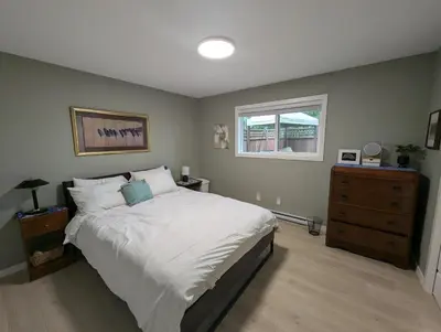 a bedroom with a bed and a dresser and a window at Colwood Hidden Home in Colwood