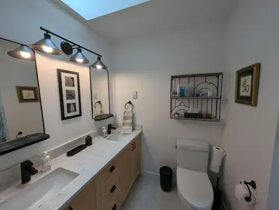 a bathroom with a sink and a toilet and a mirror at Colwood Hidden Home in Colwood