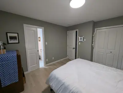 a bedroom with a white bed and two doors at Colwood Hidden Home in Colwood