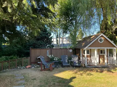 a small house with chairs and a table in a yard at Surrey Home - King George Blvd & Rapid Transit - Airport 25 Min - Free Parking & Wi-Fi in Surrey