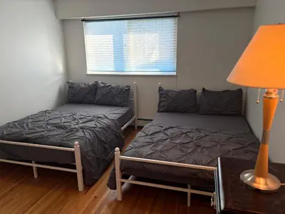 a bedroom with two beds and a lamp and a window at Vancouver Guest House - Airport & Downtown 15 Min - Free Parking & Fast Wi-Fi in Vancouver