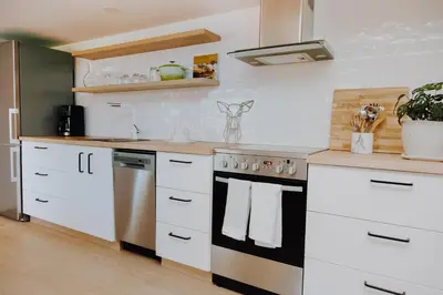 a kitchen with white cabinets and a stove top oven at Luxury 1BR at Red Mountain Ski-Bike Sauna in Rossland