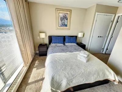 a bedroom with a bed with blue pillows and a window at Central Lonsdale Gem in North Vancouver