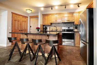 a kitchen with wooden cabinets and a bar with stools at Rocky Mountain Retreat-Mountain View! in Canmore