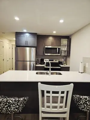 a kitchen with a sink and a counter with chairs at Livingston Calgary Lovely space in Calgary