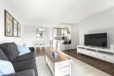 a living room with a couch and a flat screen tv at Chic & Spacious 2BR at Stampede with Parking, AC in Calgary