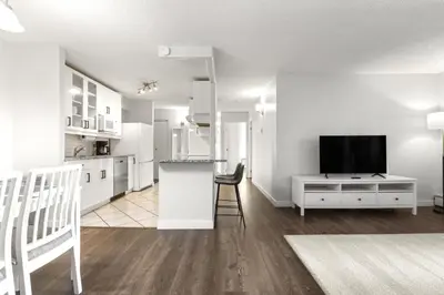 a kitchen and living room with a tv and a counter at Chic & Spacious 2BR at Stampede with Parking, AC in Calgary