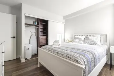 a white bedroom with a large bed and a closet at Chic & Spacious 2BR at Stampede with Parking, AC in Calgary
