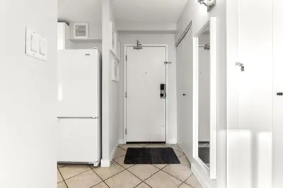 a hallway with a white door and a tile floor at Chic & Spacious 2BR at Stampede with Parking, AC in Calgary