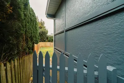 a white picket fence next to a blue building at Modern Private 2 BR with 1 bath, 3 beds, West Van in West Vancouver