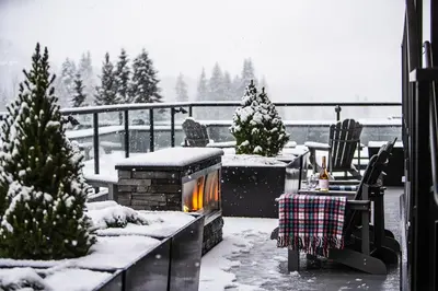 a snow covered backyard with a fireplace and christmas trees at Wooley Terrace by Revelstoke Vacations in Revelstoke