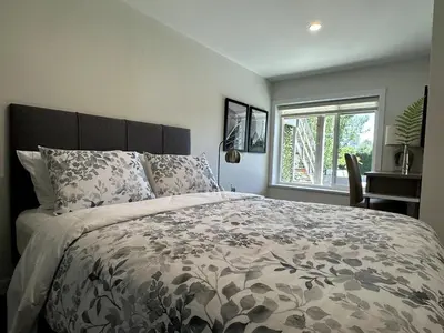 a bedroom with a bed and a desk and a window at 2BD cozy guest suite in West Vancouver! in West Vancouver